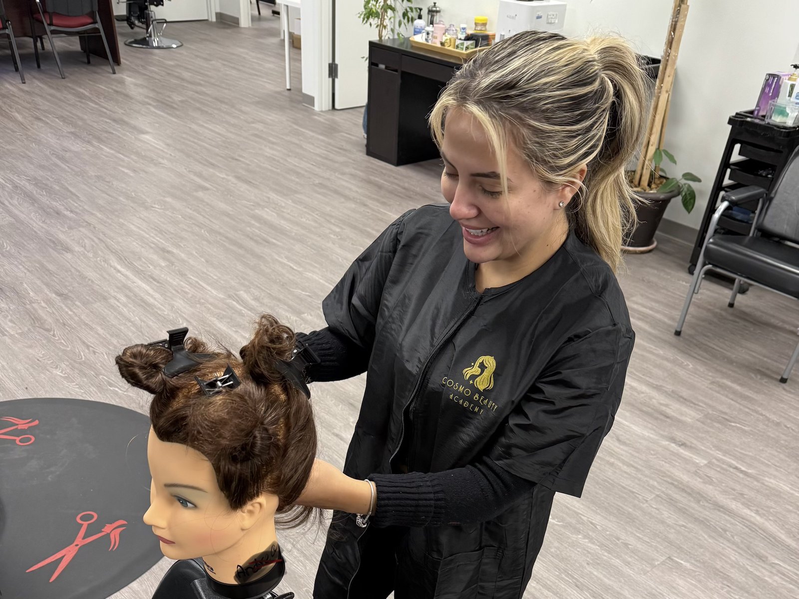 A Cosmo Beauty Academy cosmetology student sectioning and styling hair on a mannequin head