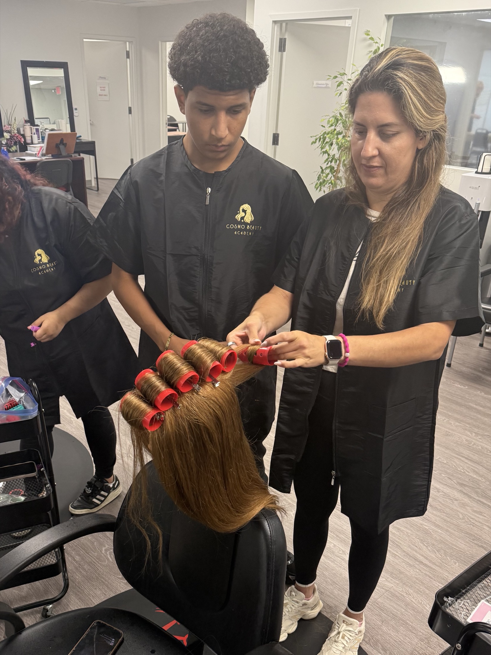 A Cosmo Beauty Academy instructor teaching a cosmetology student hair styling techniques in the classroom in Saddle Brook, New Jersey